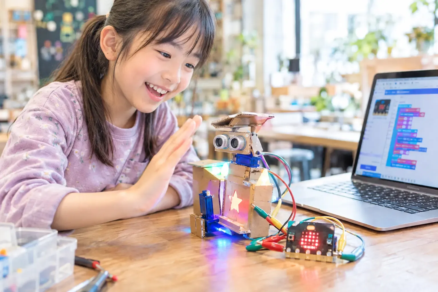 micro:bitで動く段ボールロボットに手をかざす子ども